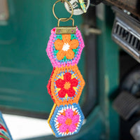 Colorful crocheted keychain with floral patterns hanging inside a vehicle.
