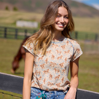 Woman wearing a patterned shirt with horses in an outdoor setting